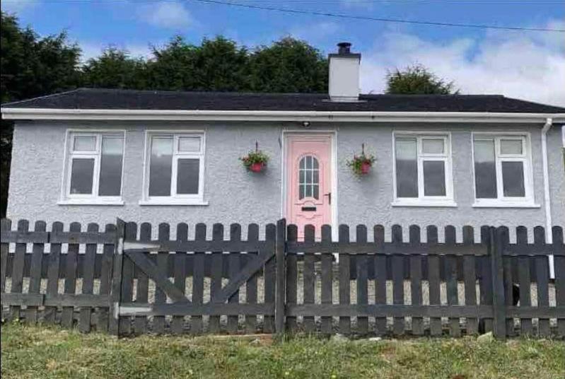 una casa blanca con una valla delante en Windmill cottage, en Donegal