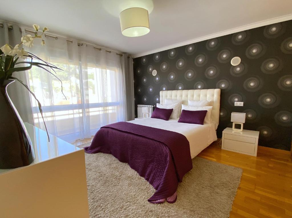 a bedroom with a bed with purple sheets and a window at Jardins da Parede 211 in Parede