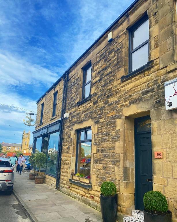 a brick building with a blue door on a street at Farndale House-Hot tub in Amble