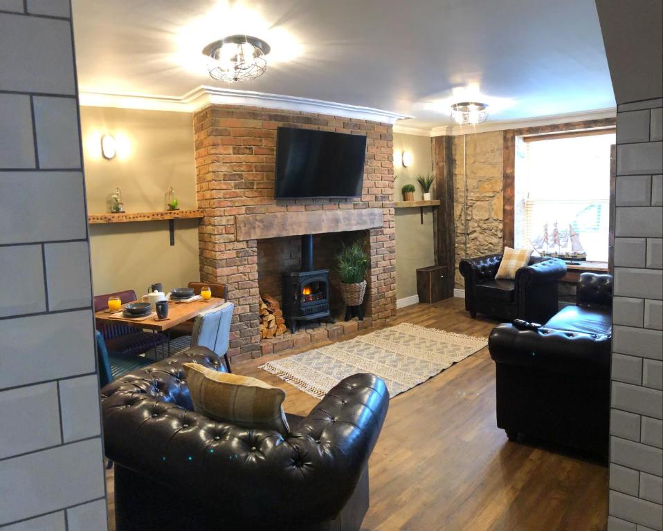 a living room with leather furniture and a fireplace at The Wynd Cottage in Amble