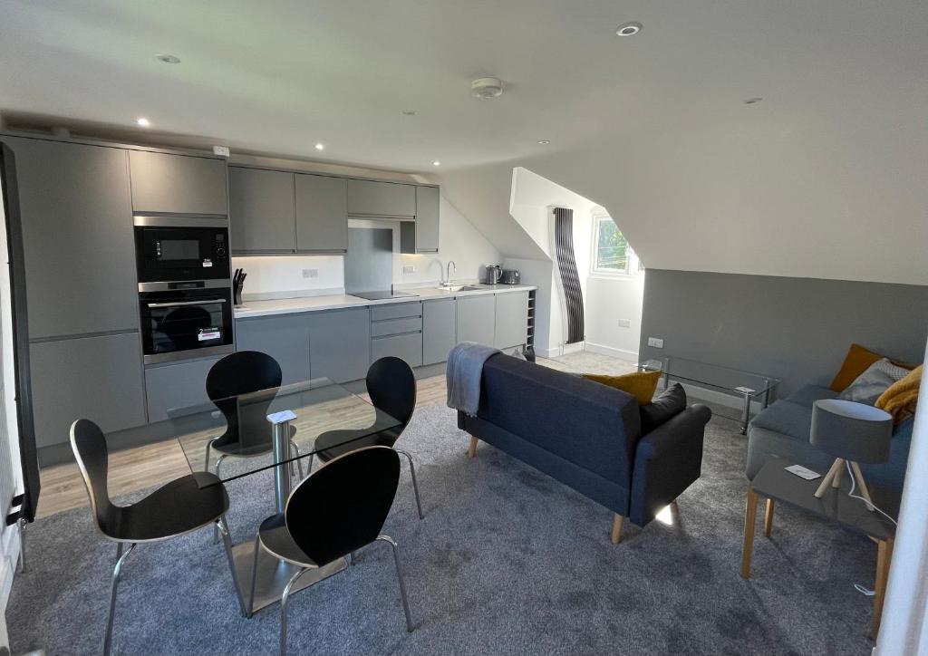a kitchen and living room with a blue couch and chairs at BH - Luxurious 1 bed top floor apartment with parking - please read about score in Shottery
