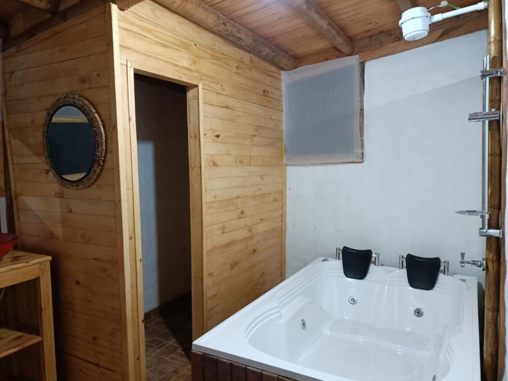 a bathroom with a white tub and wooden walls at El Refugio del Oso de Anteojos in Fómeque