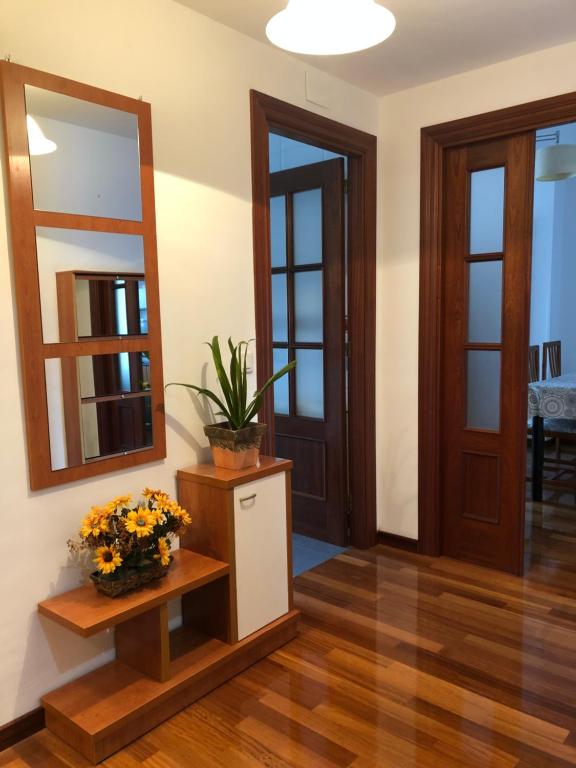 a hallway with a mirror and a table with flowers at PISO con GARAJE en AVILES in Avilés