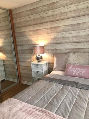 1 dormitorio con 1 cama con pared de madera en Double room with en-suite. Central for North West, en Rainhull