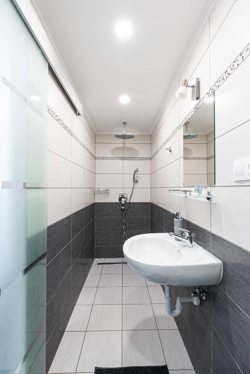 a white bathroom with a sink and a mirror at Maul - Lator vendégház in Villány