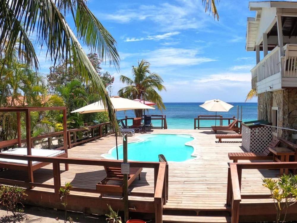 a resort deck with a swimming pool and the ocean at Coconut Tree West Bay in West Bay