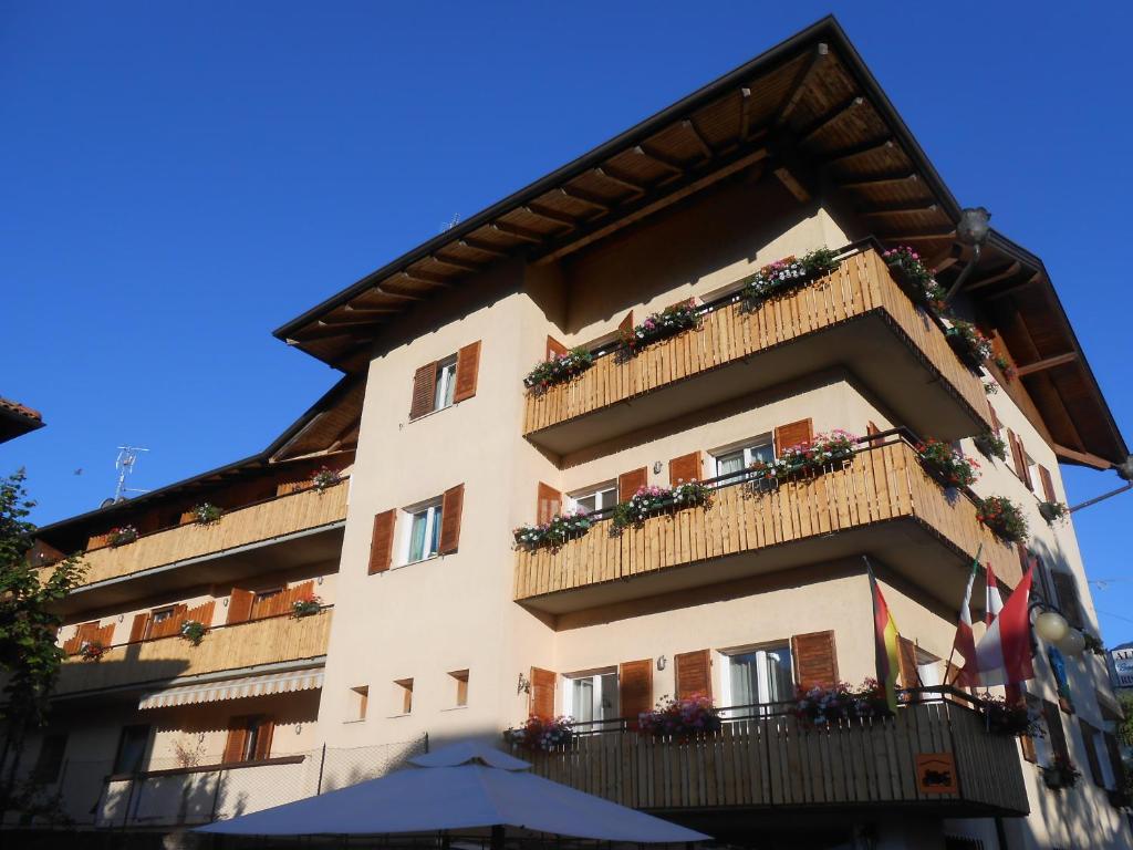 a building with a balcony with flowers on it at Albergo Genzianella in Fiavè