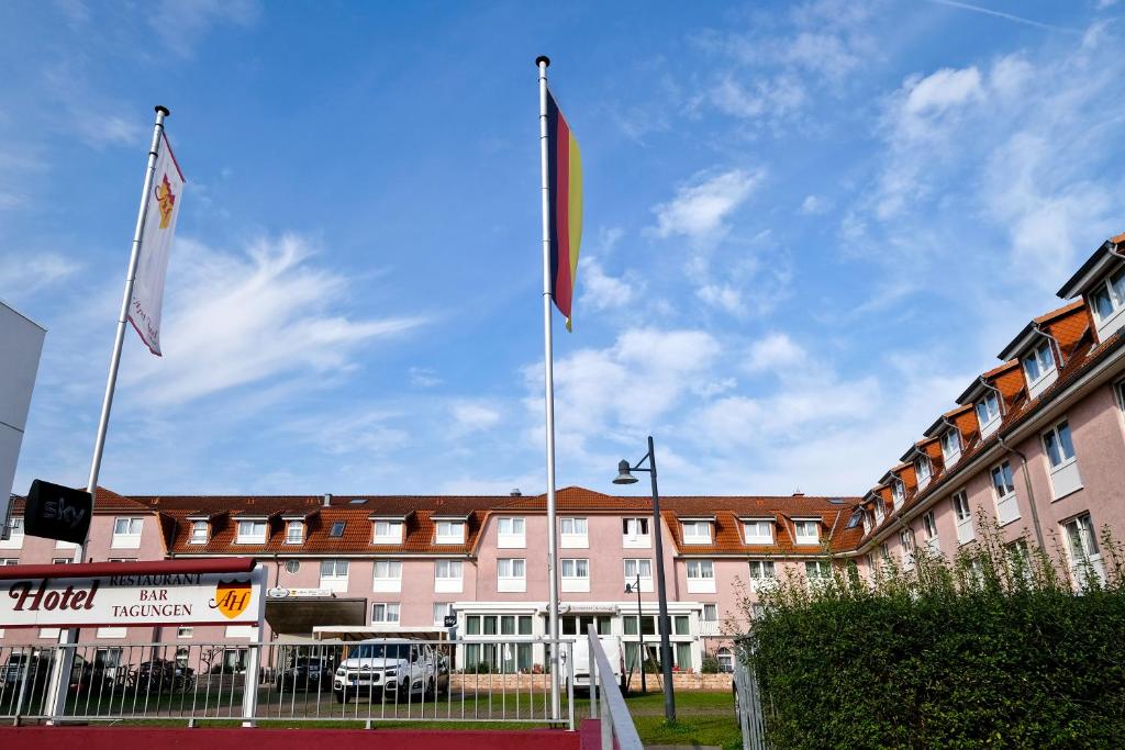 ein Hotel mit zwei Flaggen vor einem Gebäude in der Unterkunft Apart Hotel Sehnde in Sehnde