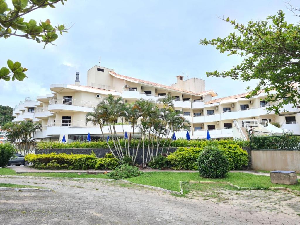 um grande edifício branco com palmeiras em frente em Praia Brava Hotel em Florianópolis