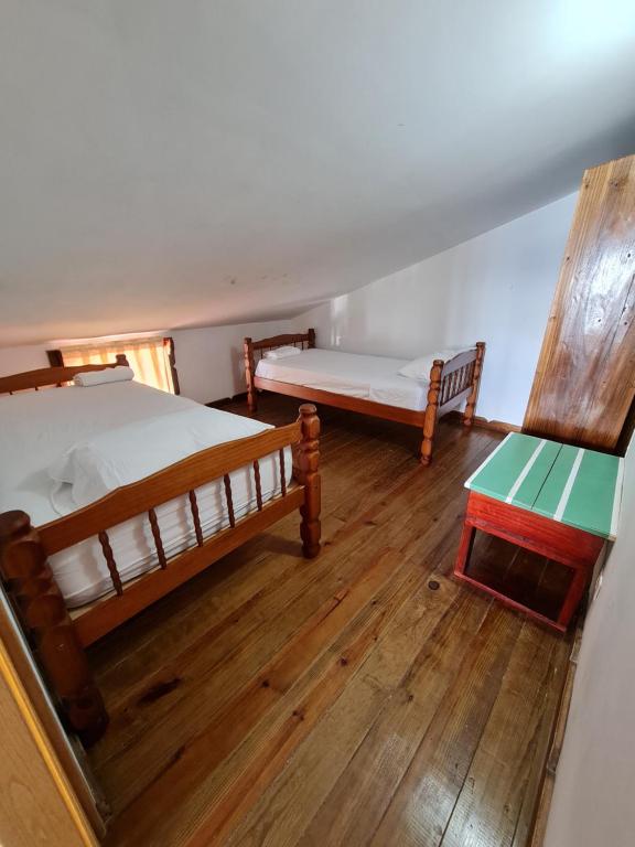 two beds and a table in a room with wooden floors at Hotel Caribbean View in Bastimentos