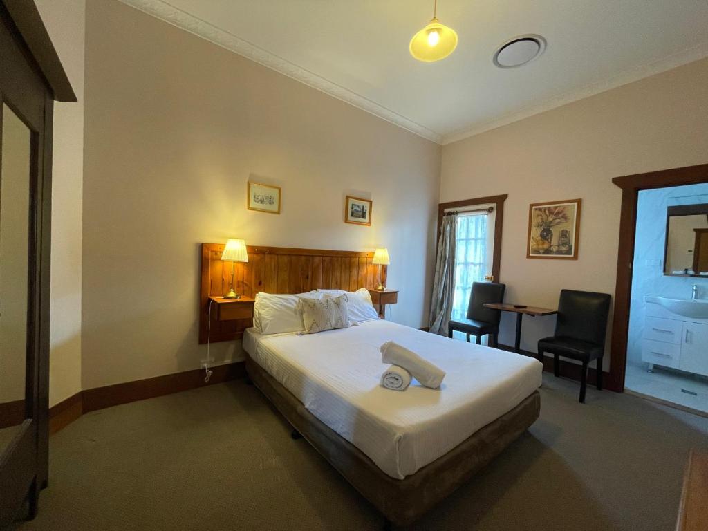 um quarto com uma cama, uma mesa e cadeiras em Belgravia Mountain Guest House em Katoomba