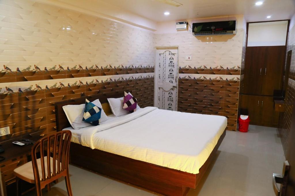 a bedroom with a bed and a chair in a room at Sri Mahalakshmi Deluxe Lodging Arakonam in Arakkonam