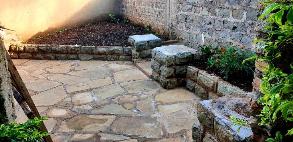 a stone patio with two stone seats in a garden at Jaaja's - The Residence, Garden and Suites near Ciala Resort Hotel Kisumu in Kisumu