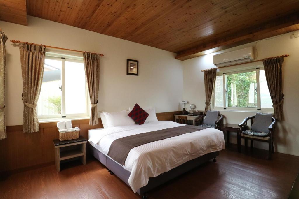 a bedroom with a large bed and two windows at Countryside B&amp;B in Ruisui