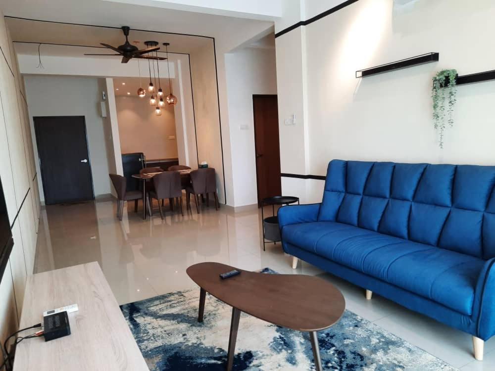 a living room with a blue couch and a table at The Awantara Homestay - Seroja Hills in Sepang
