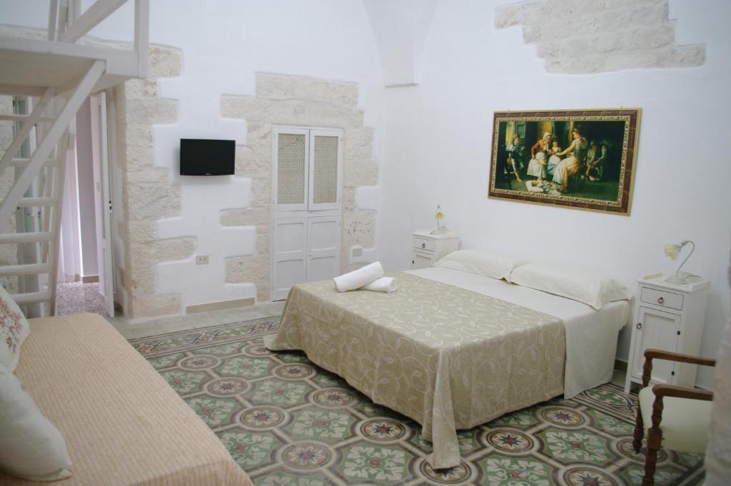 1 dormitorio con 1 cama y una pintura en la pared en B&B Aia Vecchia, en Cisternino