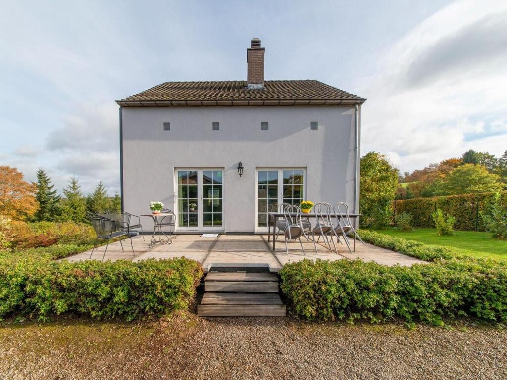 a white house with chairs and a table in front of it at Lovely Holiday Home in Ardennes Luxembourg in La-Roche-en-Ardenne