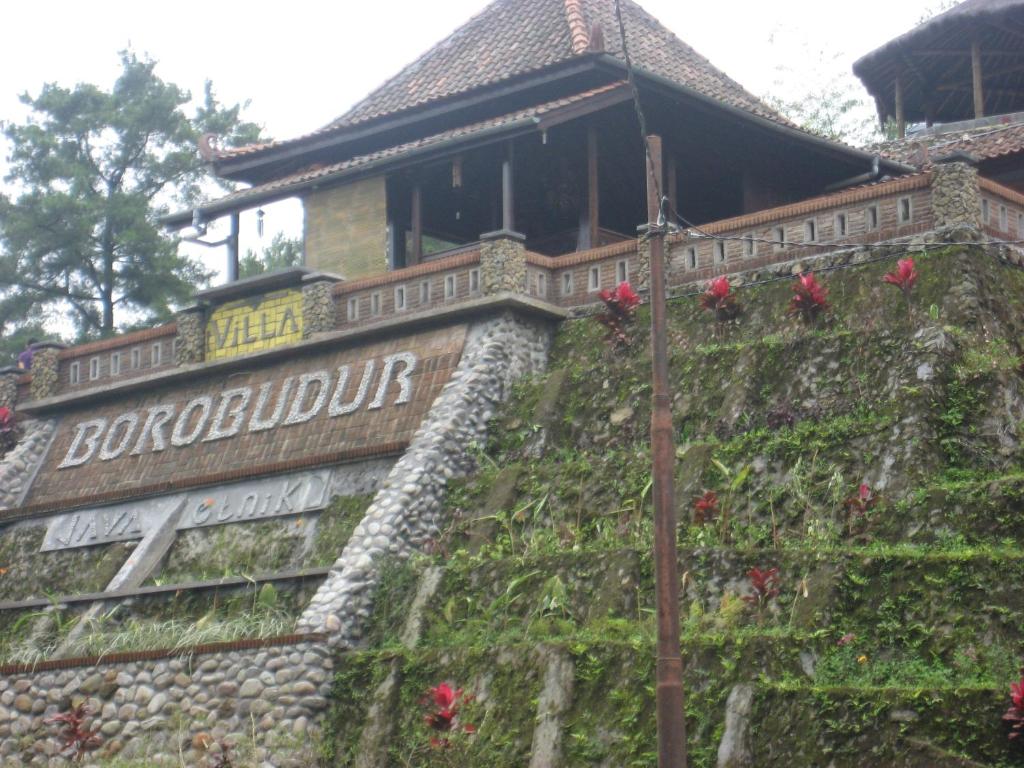 un cartel en una pared con flores. en Villa Borobudur Malino 