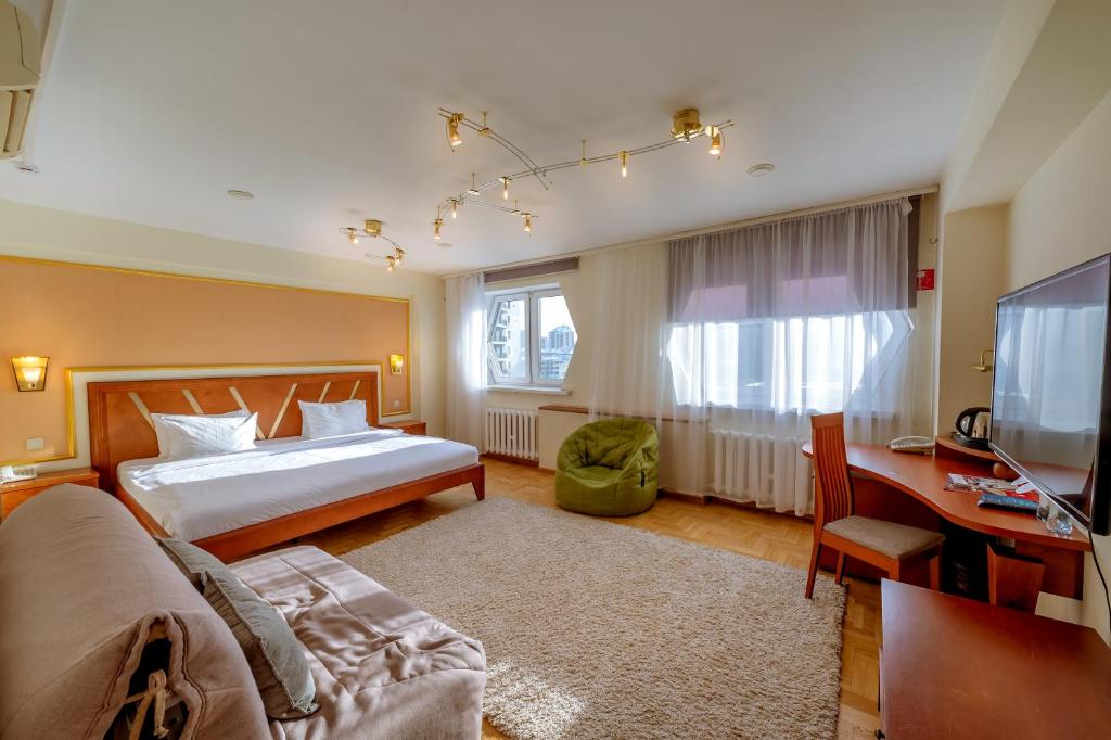 a bedroom with a bed and a desk and a television at AZIMUT Hotel Siberia in Novosibirsk
