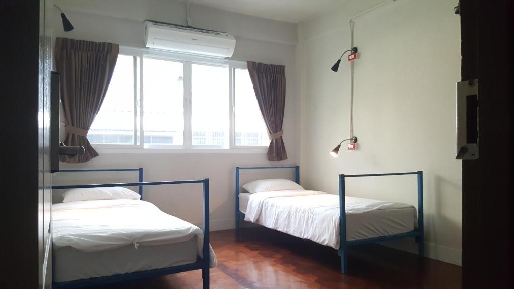 two beds in a room with a window at Bangkok Check Inn @Chareon Krung in Bangkok