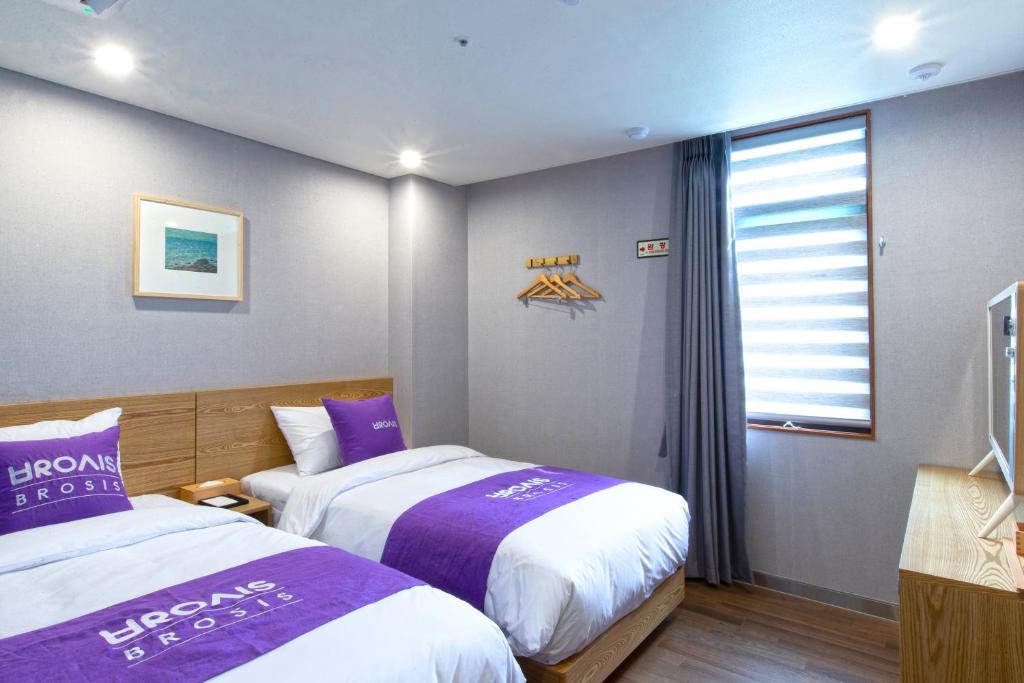 a hotel room with two beds and a window at Brosis Hotel in Busan