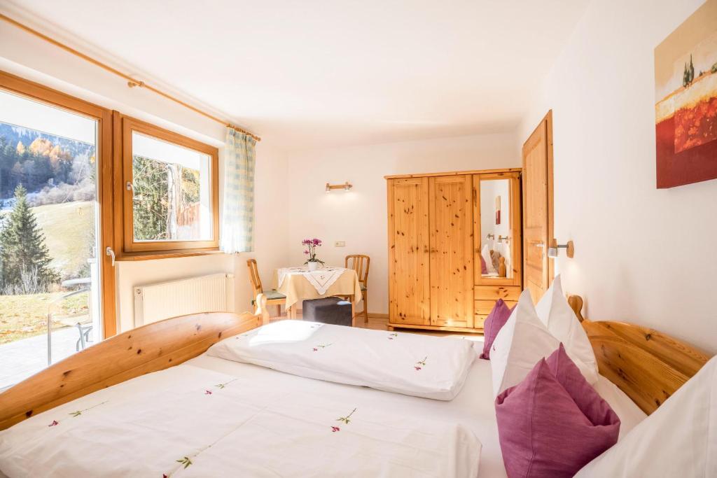 ein Schlafzimmer mit einem Bett und einem großen Fenster in der Unterkunft Bnb Lettnerhof Terrace Family Suite in Welsberg-Taisten