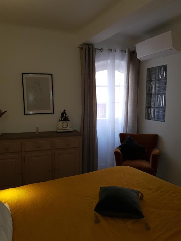 a bedroom with a bed and a chair and a window at Maison de ville Forum Julii in Fréjus
