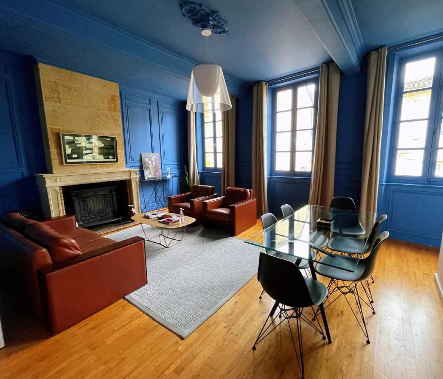 uma sala de estar azul com uma mesa de vidro e cadeiras em La Petite Fontaine em Saint-Émilion