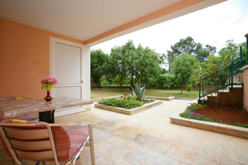 a patio with a table and chairs and a garden at Apartments Neda - Poreč South in Poreč
