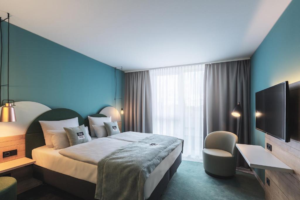 um quarto de hotel com uma cama grande e uma televisão em the niu Cure em Erlangen