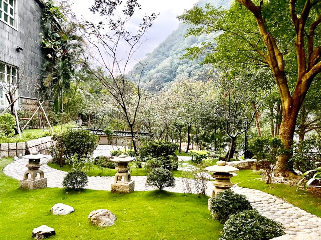 a garden with rocks and trees and a building at Uni-Resort Ku-Kuan in Heping