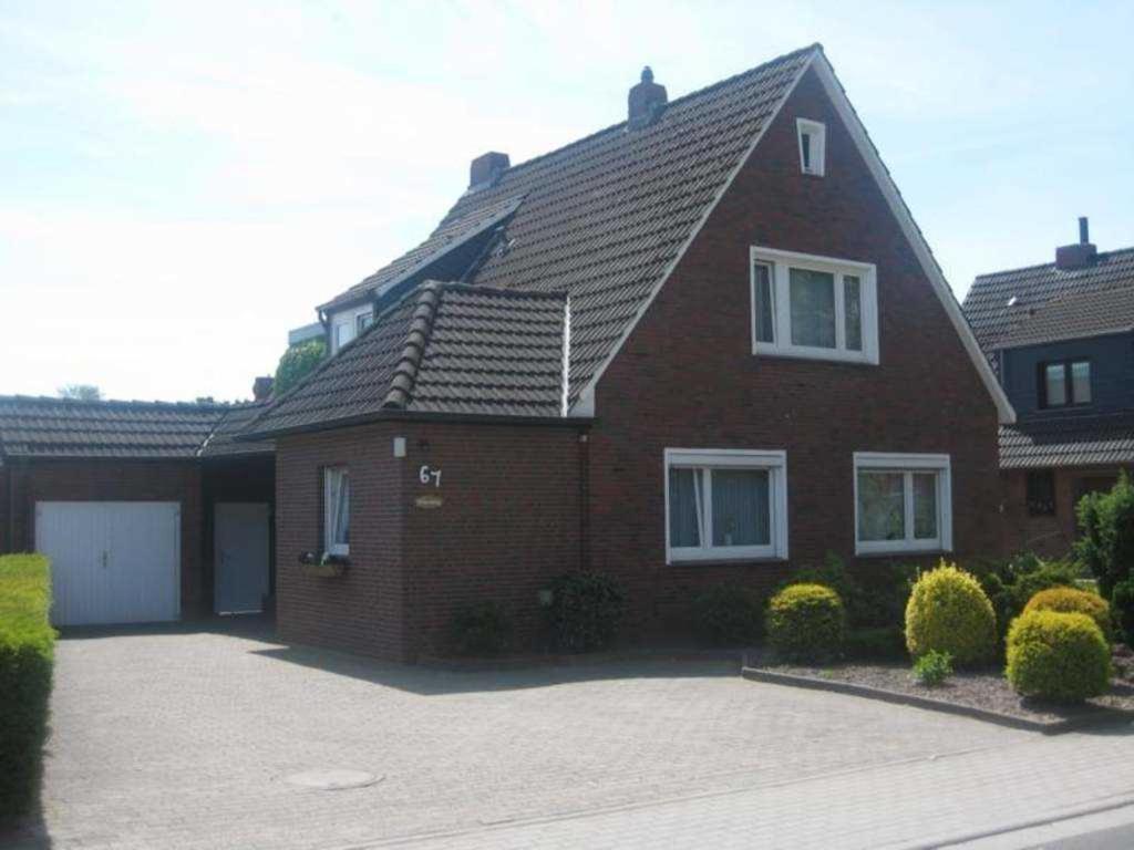 a red brick house with a driveway at Ferienwohnung Bruns 15028 in Leer