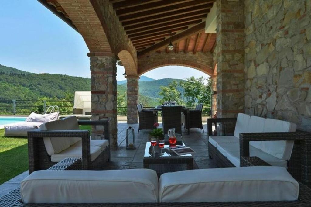 un patio al aire libre con sofás blancos y una mesa en Villa Le Croci Firenze, en Bovecchio