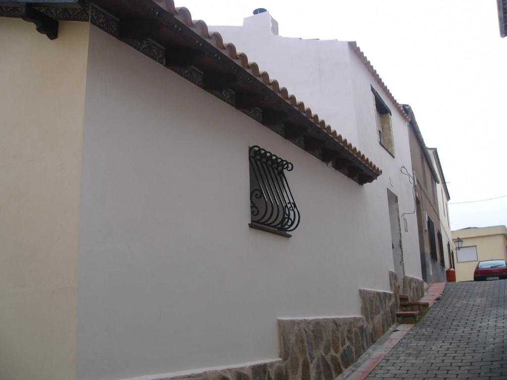 una señal negra en un lado de un edificio blanco en La Encina B, en Villaverde de Guadalimar