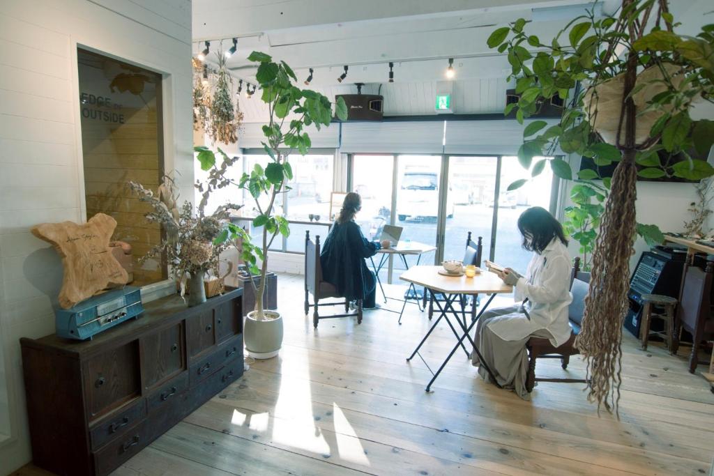 Dos mujeres sentadas en una mesa en una habitación en Atelier & Hostel Nagaisa-Ura, en Atami