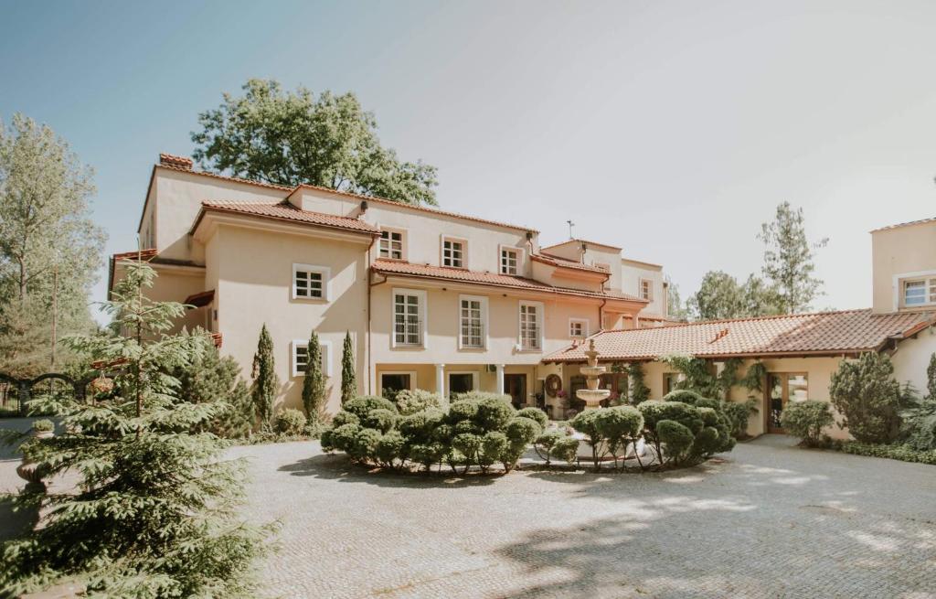 duży dom z dziedzińcem z drzewami i krzakami w obiekcie Villa Toscana Warszawa w Warszawie
