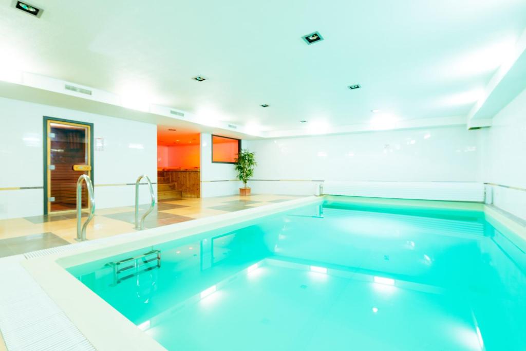 een groot zwembad in een witte kamer met bij Hotel Soret in Overijse