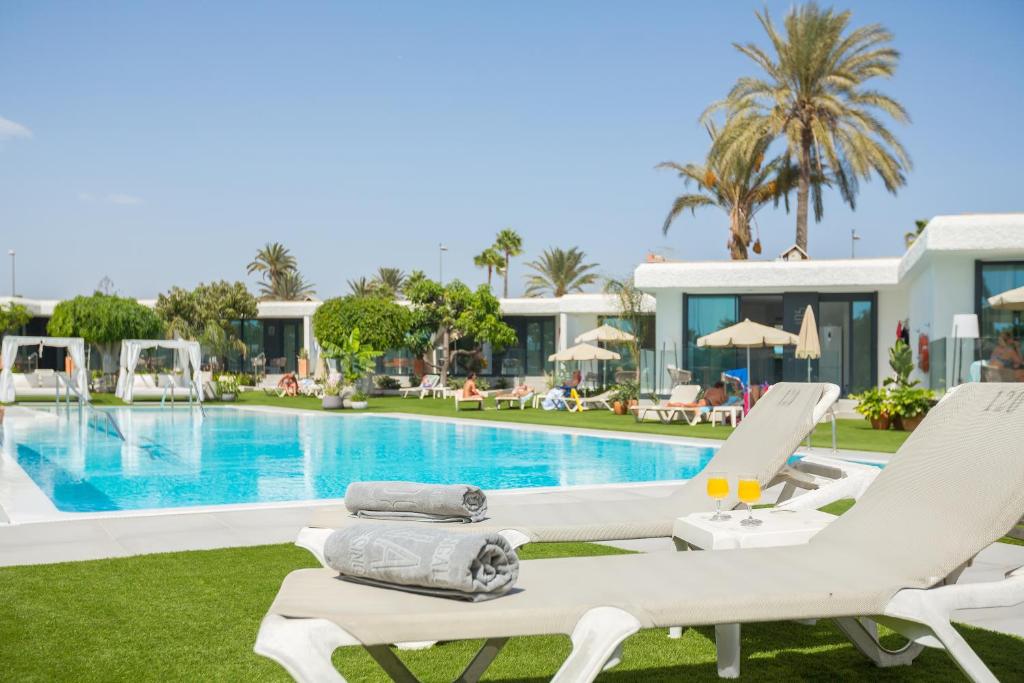 a villa with a swimming pool and lounge chairs at Bungalows Doña Rosa in Playa del Ingles