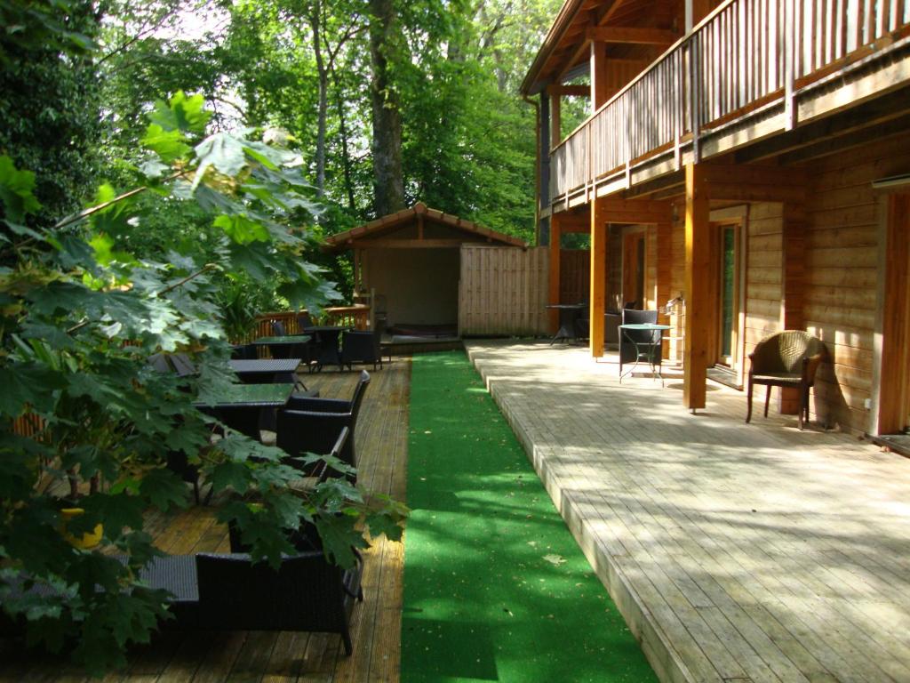 une terrasse couverte d'une maison avec une pelouse verdoyante dans l'établissement Les Grands Frênes, à Plaine-de-Walsch