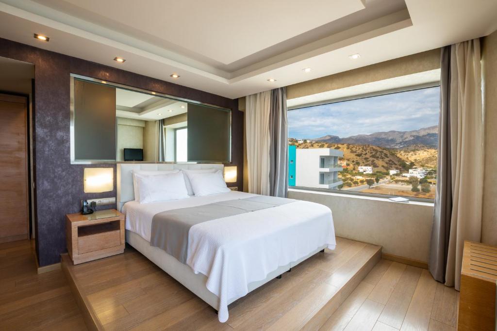 a bedroom with a white bed and a large window at Konstantinos Palace in Karpathos