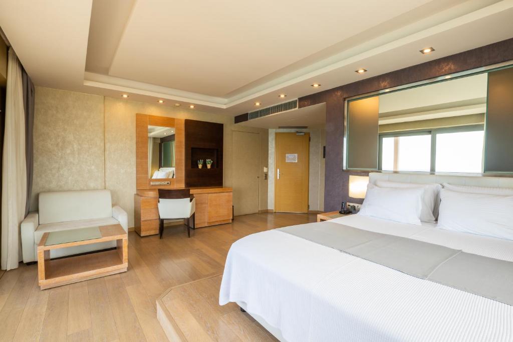 a bedroom with a large white bed and a desk at Konstantinos Palace in Karpathos