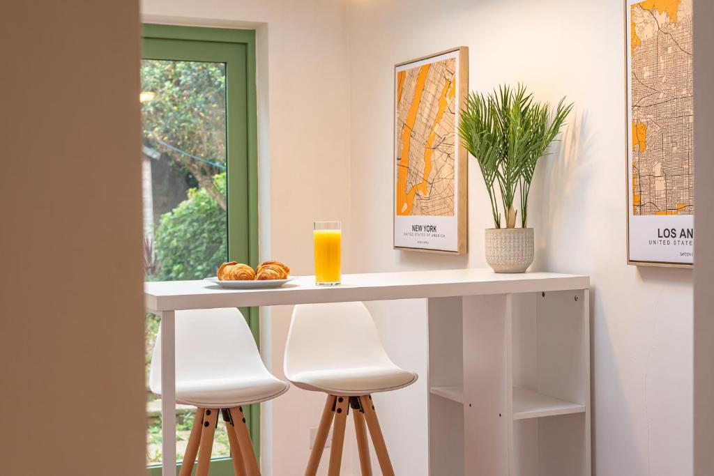 een tafel met twee krukken en een glas sinaasappelsap bij Cosy 2 Bedroom Reading House SLEEPS 6 - With FREE WiFi & Garden by Roost Accommodation in Reading