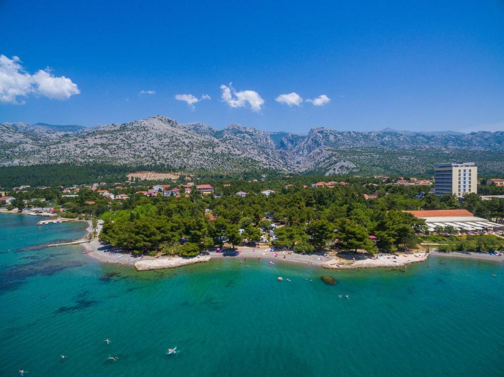 an island in the ocean with mountains in the background at Camping Paklenica in Starigrad