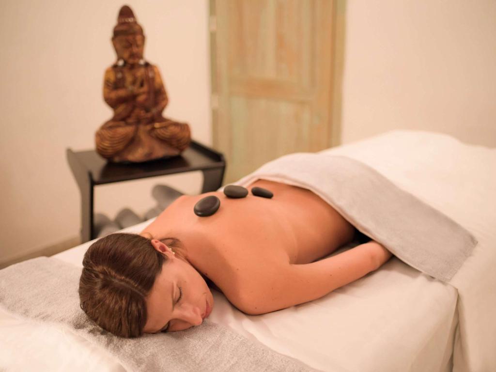 a woman laying on a bed with her head on a towel at Almar Timi Ama Resort & Spa in Villasimius