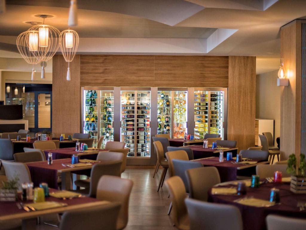 a dining room with tables and chairs and windows at Almar Timi Ama Resort & Spa in Villasimius