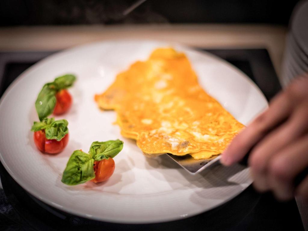 a plate of food with a piece of omelette and tomatoes at Almar Timi Ama Resort & Spa in Villasimius