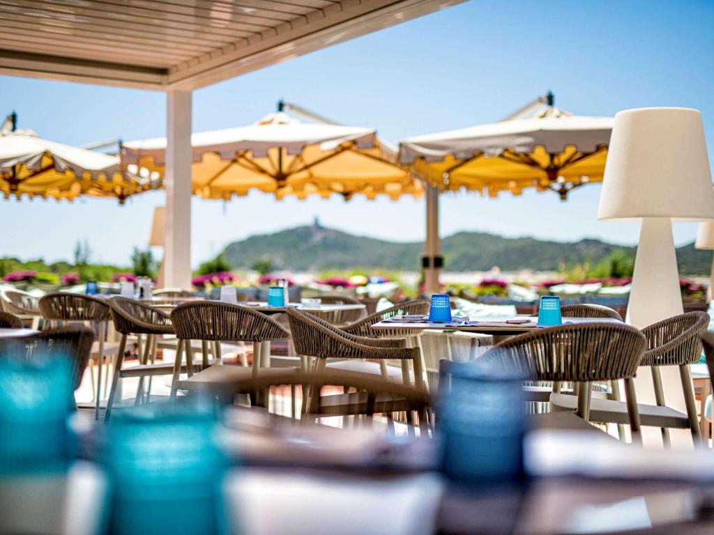 a group of tables and chairs with yellow umbrellas at Almar Timi Ama Resort & Spa in Villasimius