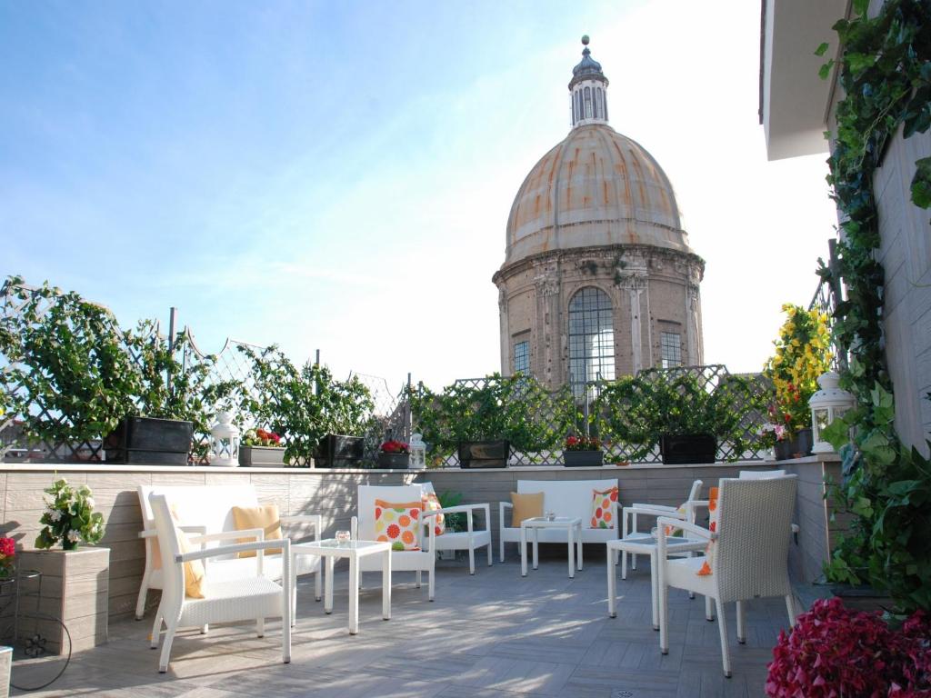 a patio with white chairs and a building in the background at Hotel San Pietro in Naples