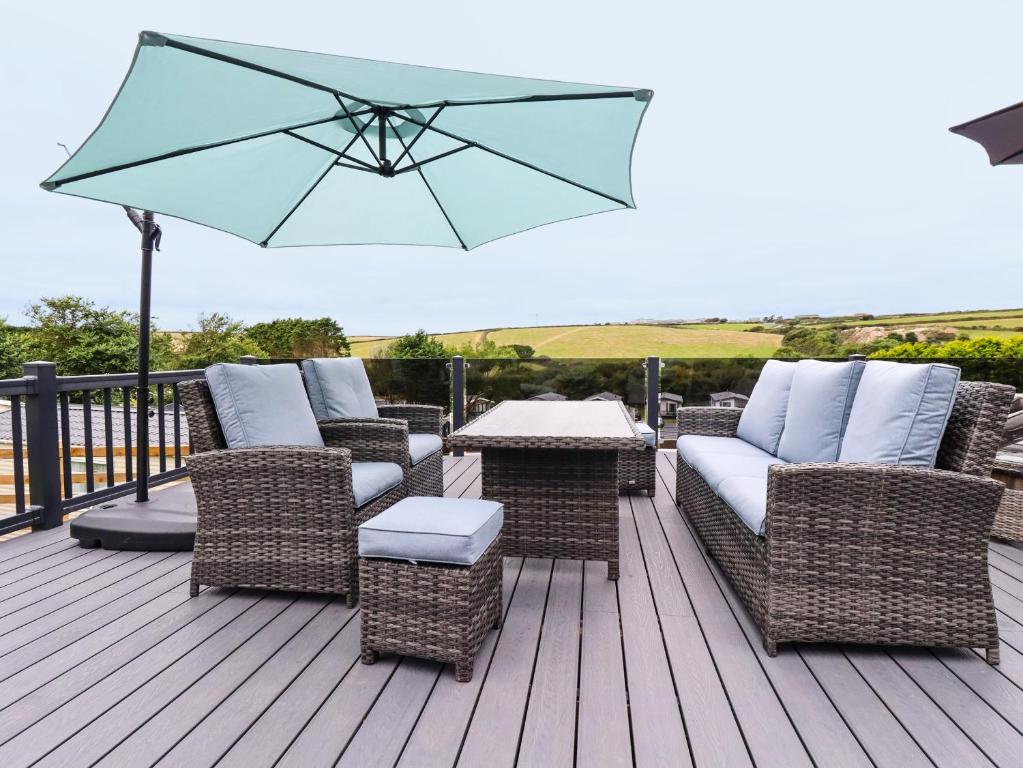 a deck with wicker chairs and a table with an umbrella at Beachcliff in Newquay