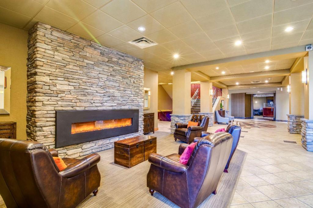 a lobby with leather chairs and a stone fireplace at Quality Hotel & Conference Centre Sawridge in Peace River